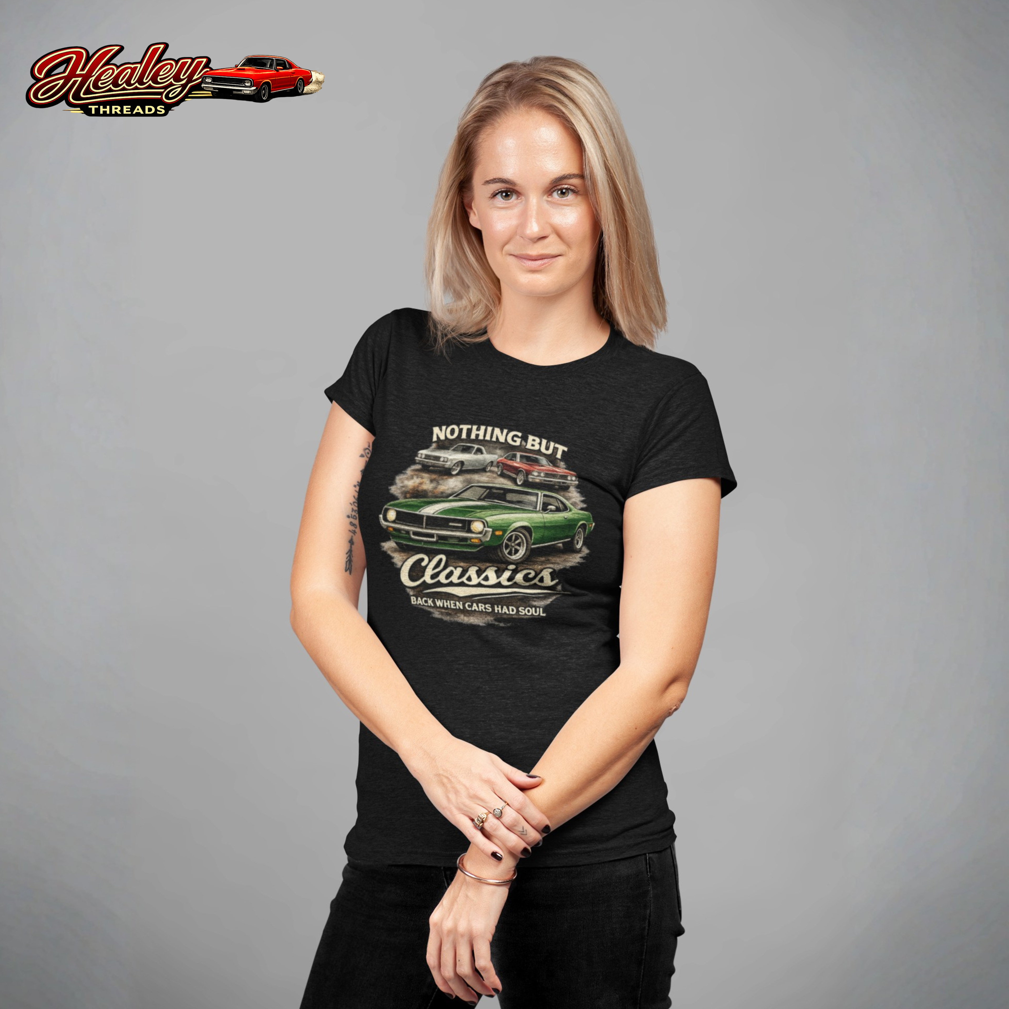Woman wearing a black t-shirt with a graphic design on a gray background, featuring the 'Healey Threads' brand.