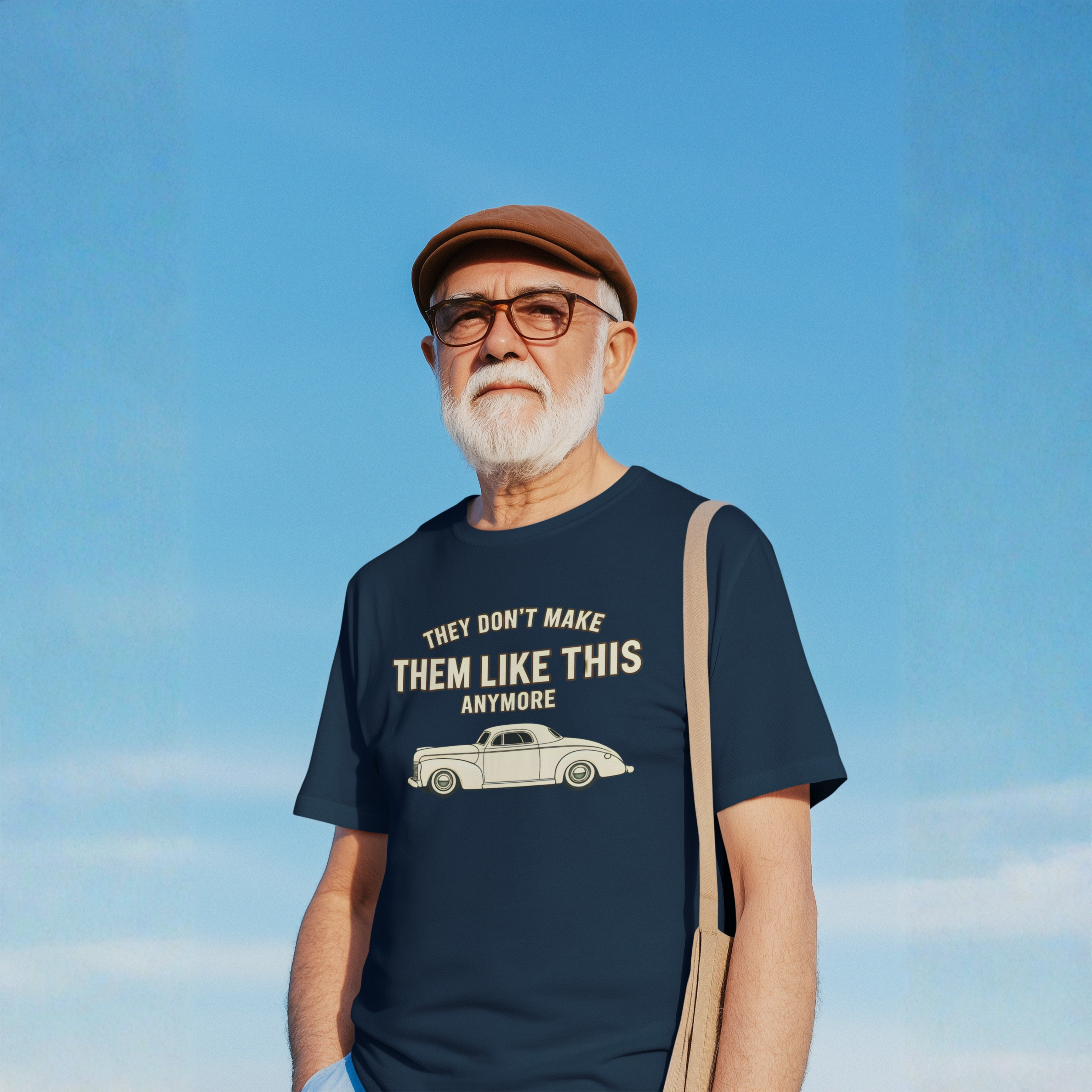 Man wearing a navy blue t-shirt with a graphic and text against a clear blue sky.