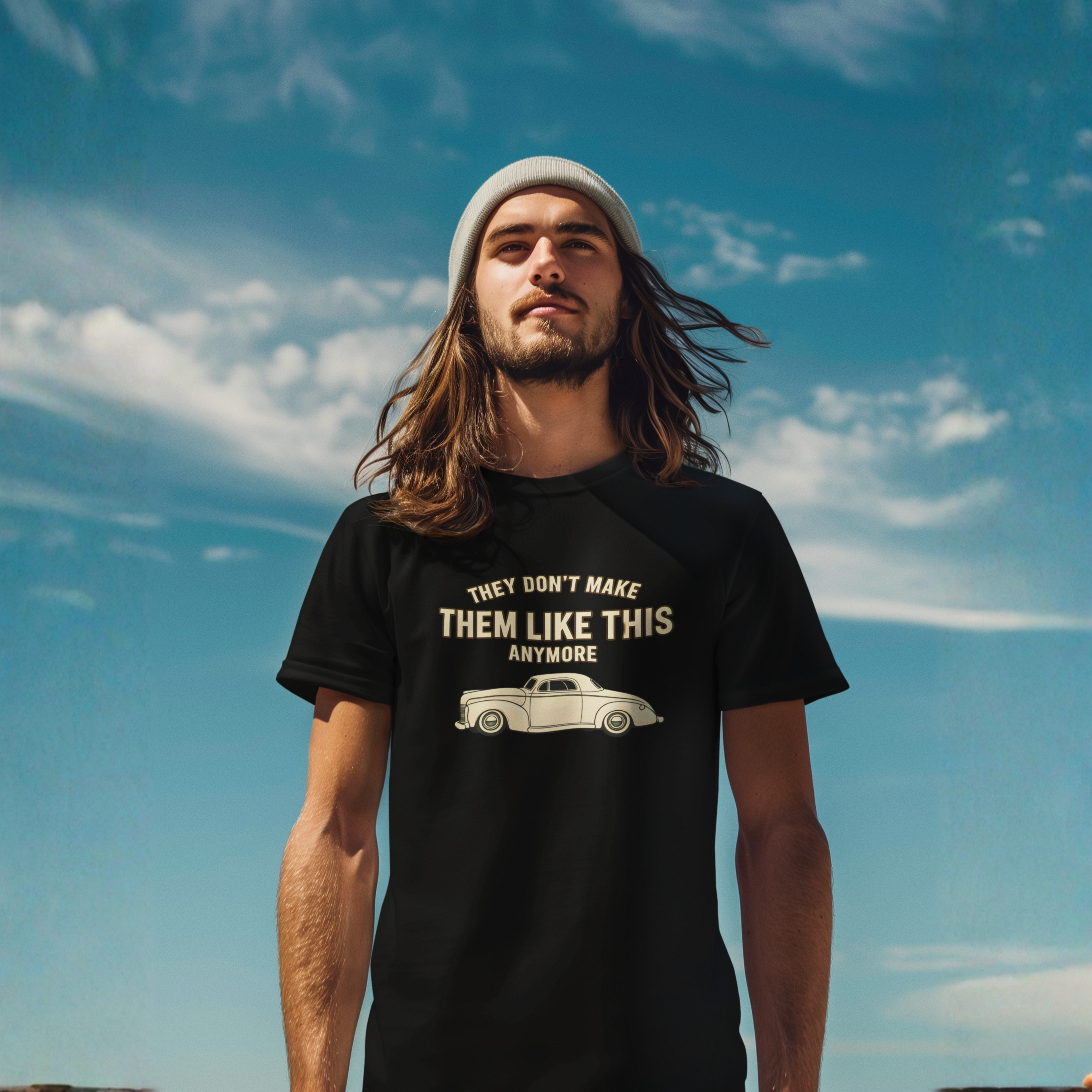 Beaded man wearing a black t-shirt with a graphic and text against a blue sky.