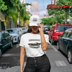 Girl wearing a white t-shirt with a graphic vintage vette design and text, standing on a street with cars and palm trees in the background.