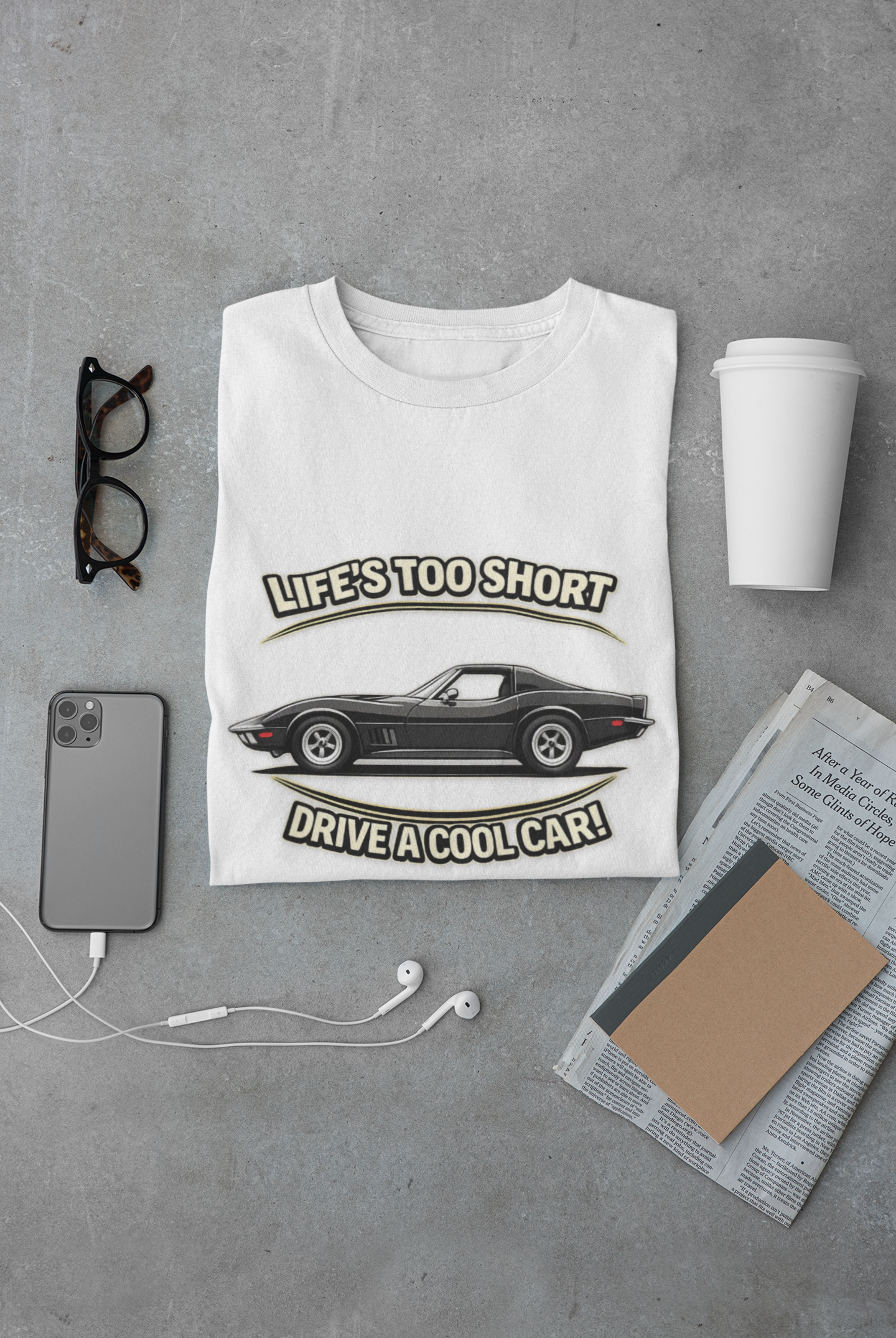 White t-shirt with vintage vette graphic and text on a gray surface with accessories.