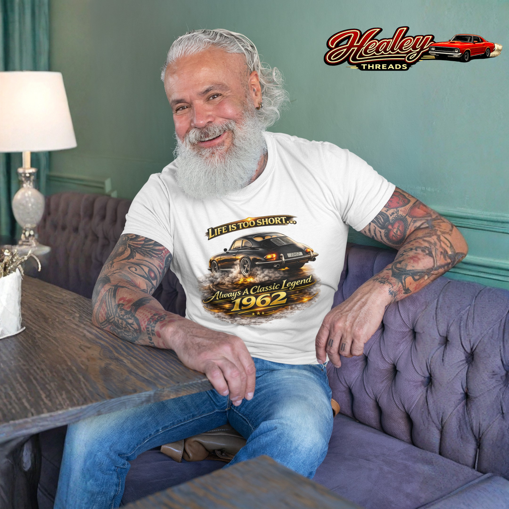 Man sitting on a couch wearing a white t-shirt with a classic car design, Healey Threads logo in the corner.