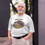 Man wearing a white t-shirt with a graphic design of a classic car and text, standing outdoors.