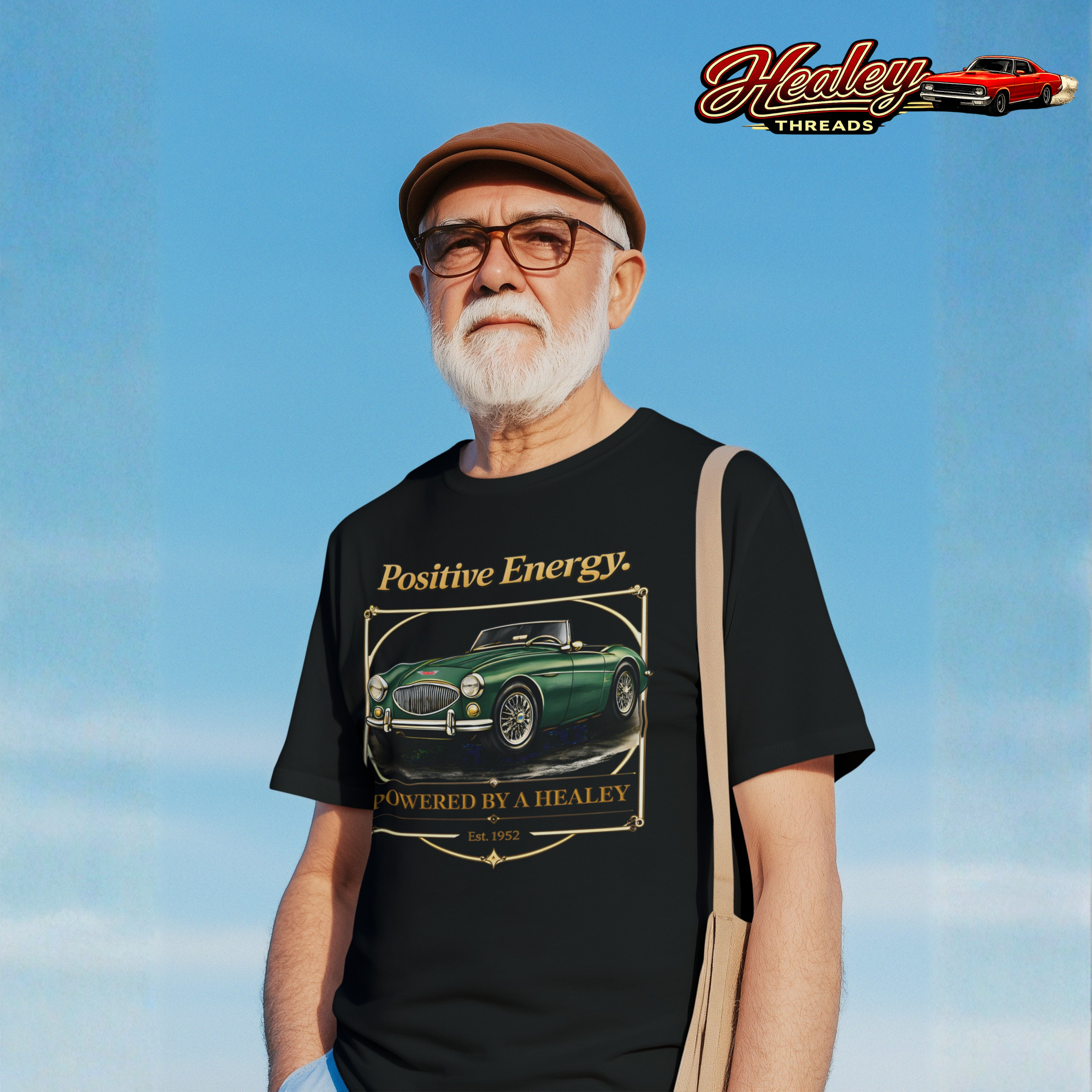 Man wearing a black t-shirt with a  classic car graphic and 'Positive Energy' text, standing against a blue sky.