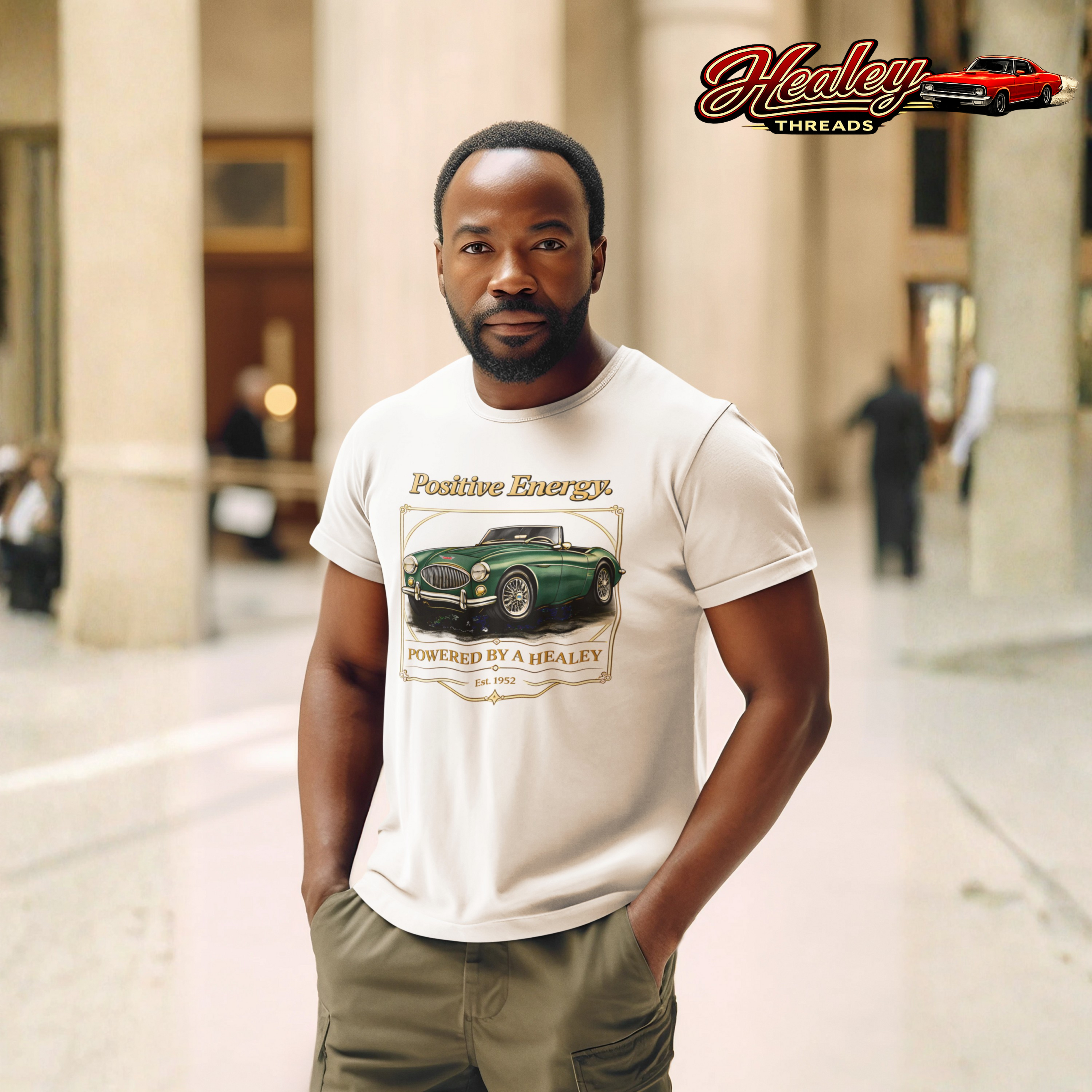 Man wearing a beige t-shirt with a graphic design of a classic green car and text, standing in an urban setting.