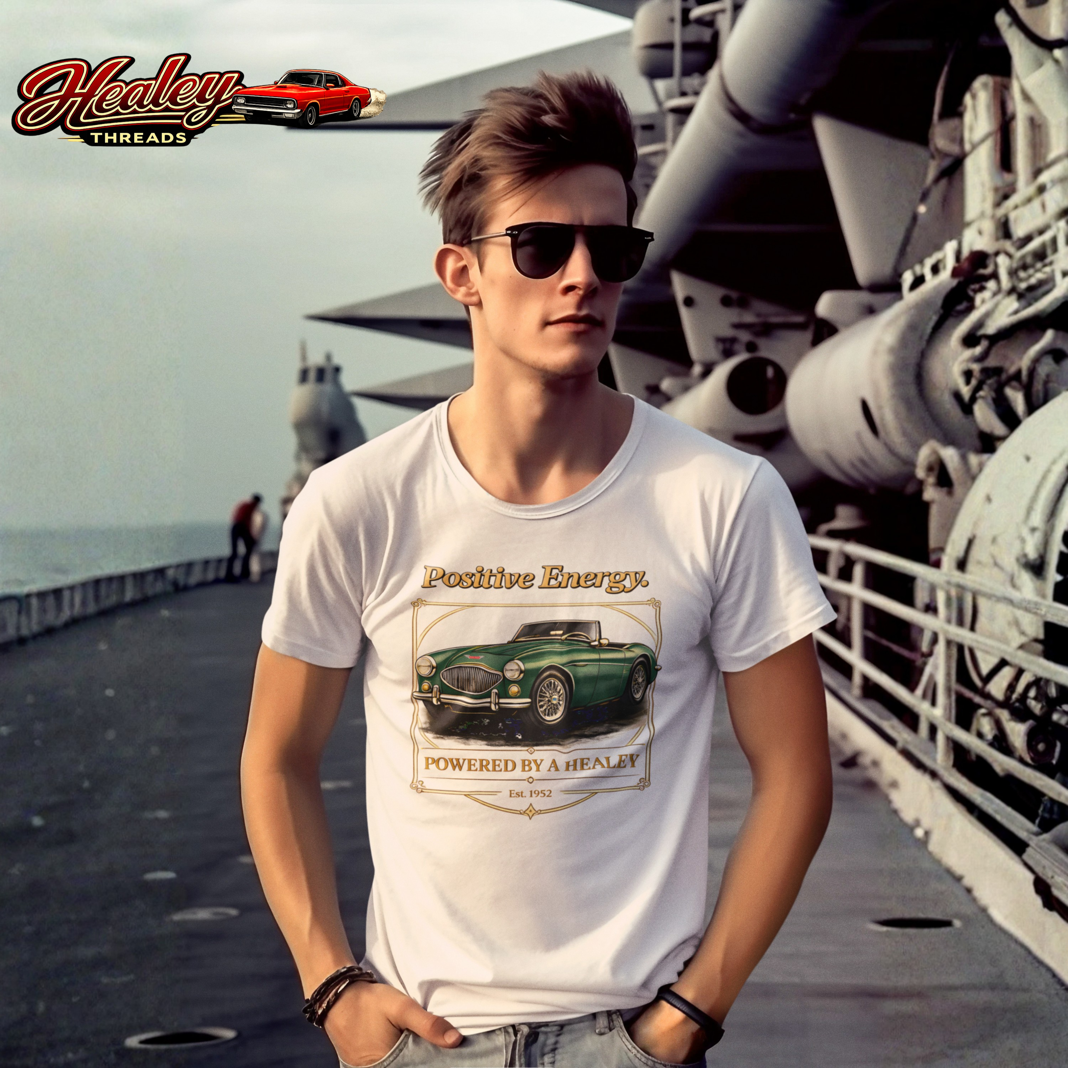 Man wearing a white t-shirt with a classic car graphic and 'Healey Threads' branding on a ship deck.