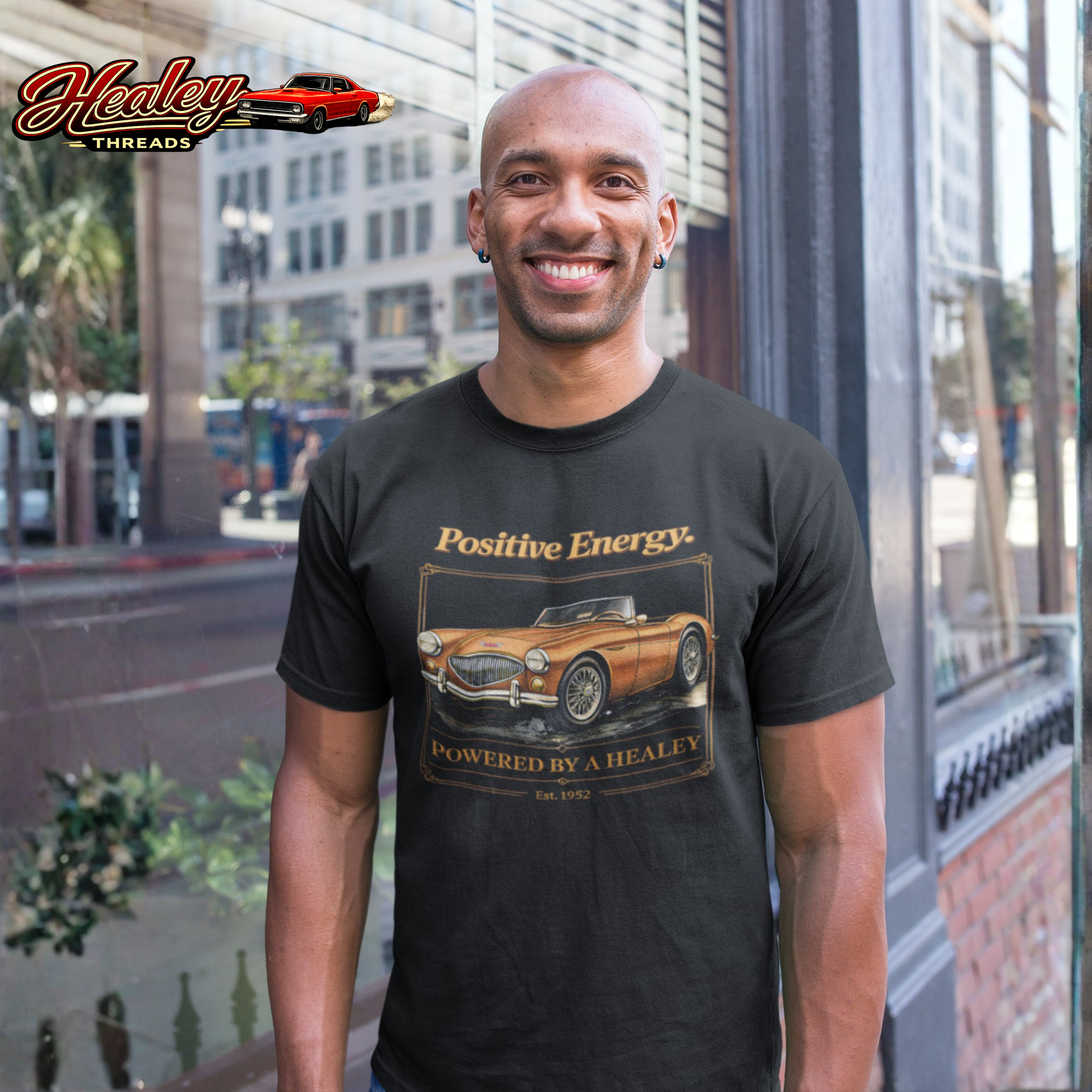 Man wearing a black t-shirt with a vintage car design and 'Healey Threads' branding.