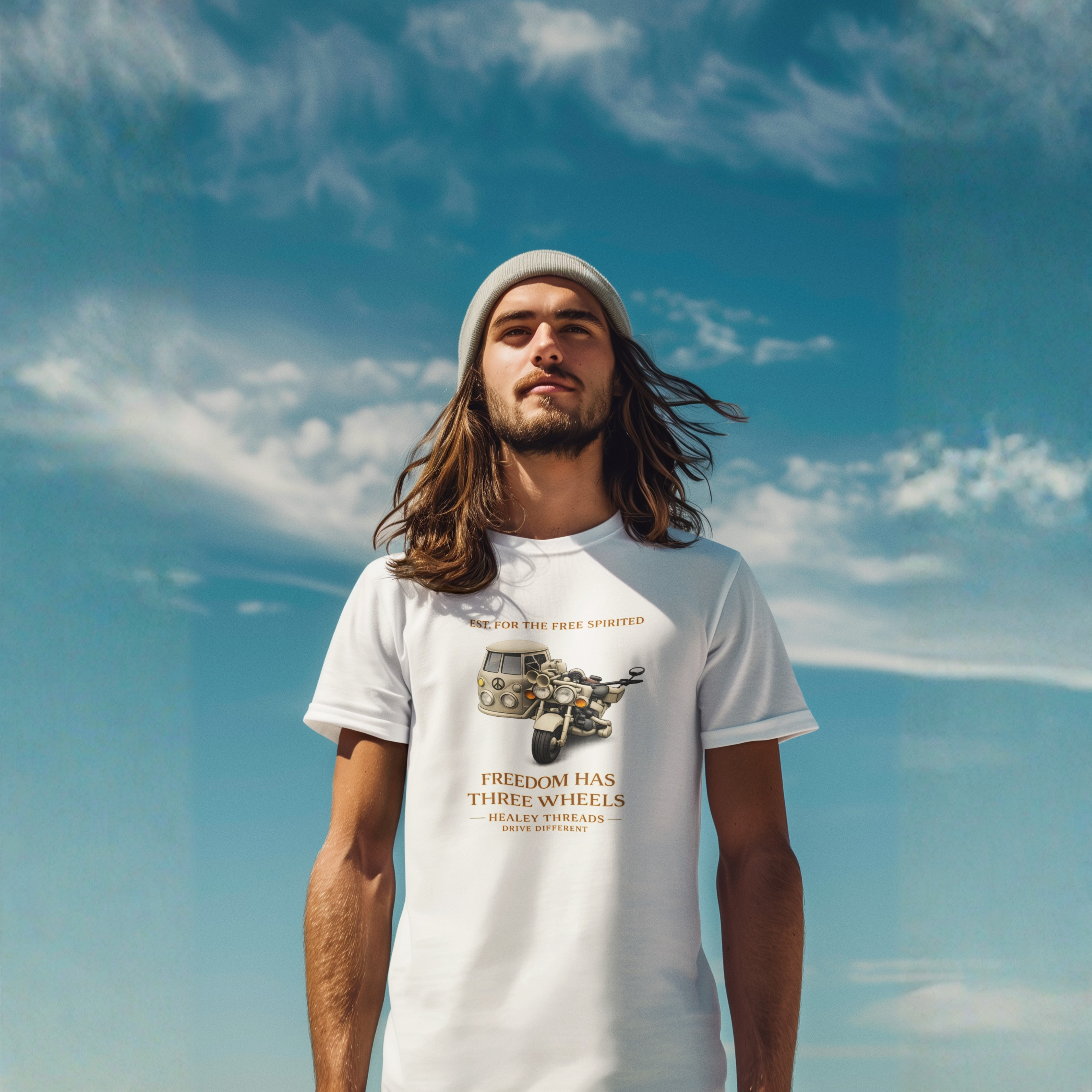 Man wearing a black t-shirt with Cream motorcycle-sidecar van mashup with peace symbol and gold "Freedom Has Three Wheels" text against a blue sky