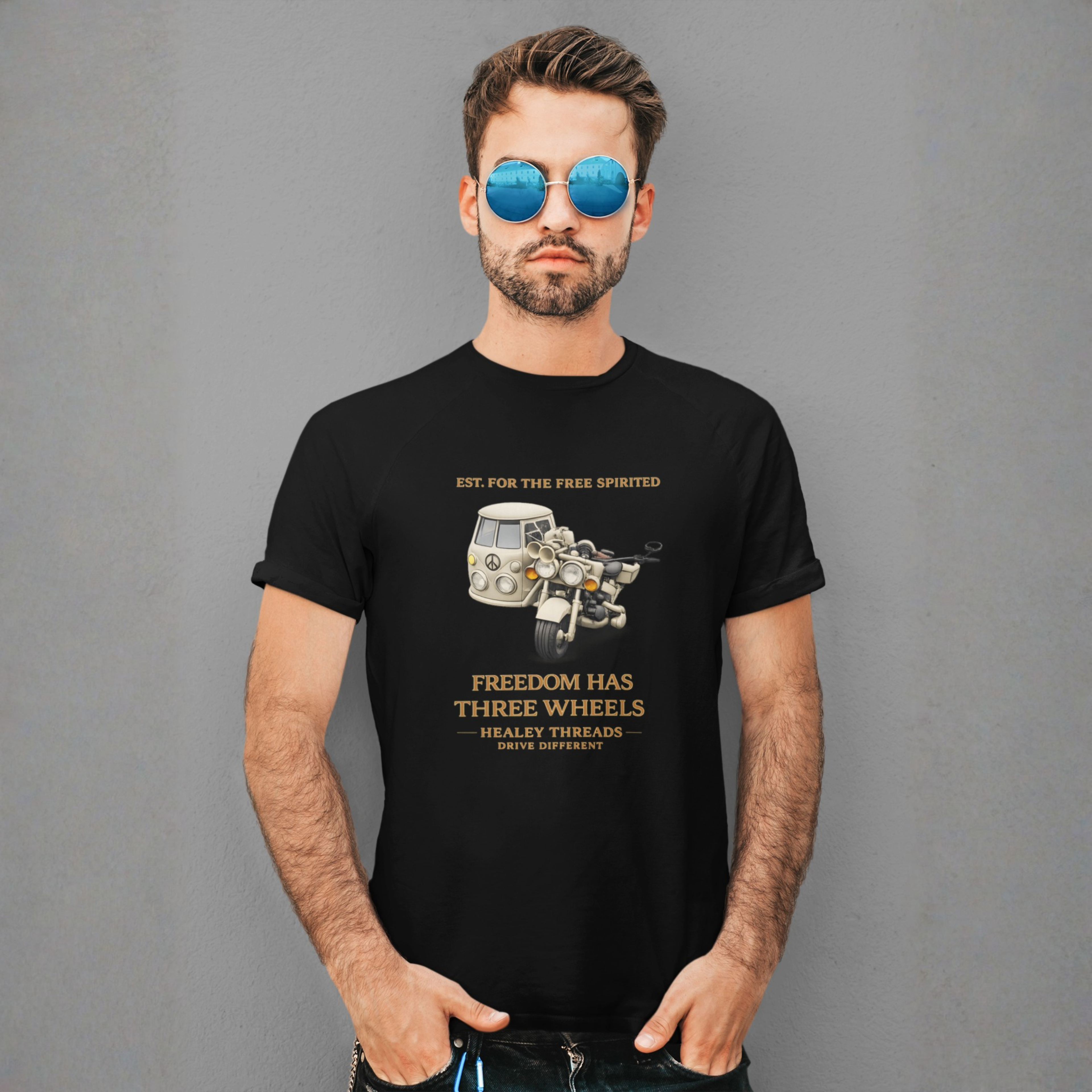 Man in black tee with retro motorcycle-sidecar van graphic and gold 'Freedom Has Three Wheels' text