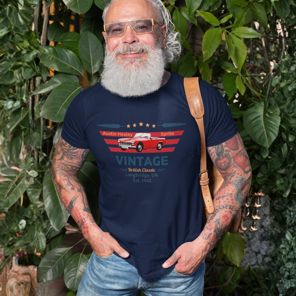 Man wearing a navy blue t-shirt with a vintage car design, standing among green foliage.