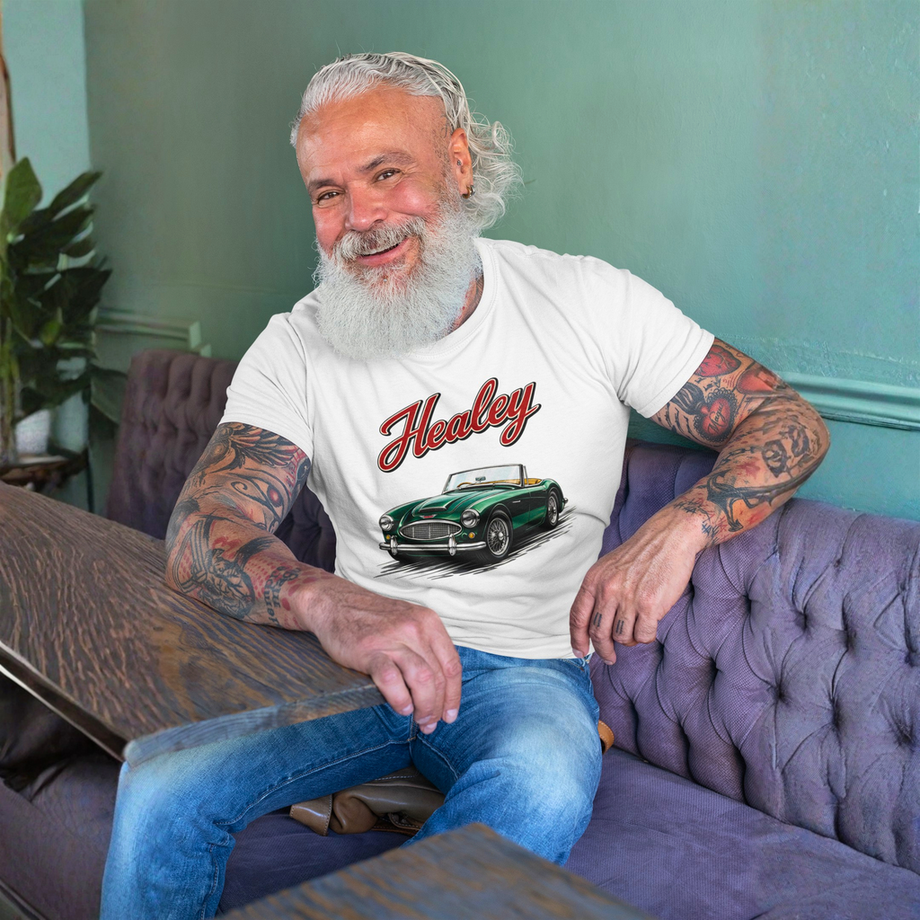 Man sitting on a purple couch wearing a white t-shirt with a vintage car graphic and 'Healey' text.