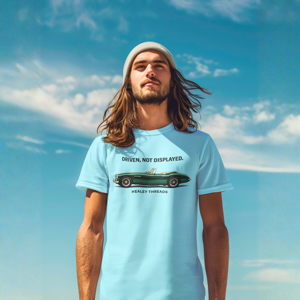 Man wearing a light blue t-shirt with a classic car graphic design against a blue sky.