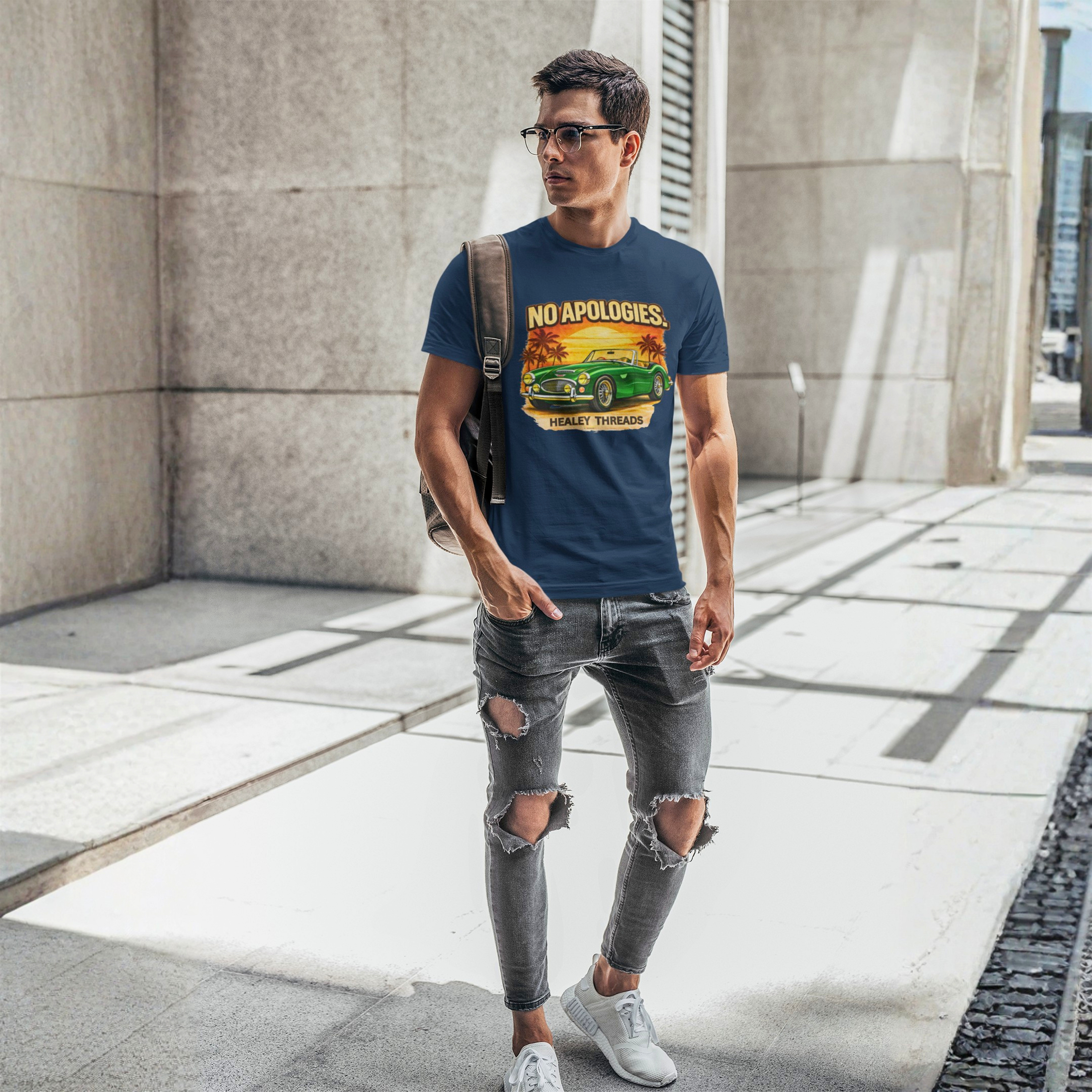 Man wearing a blue t-shirt with a graphic Healey car design and text, standing on a city street.