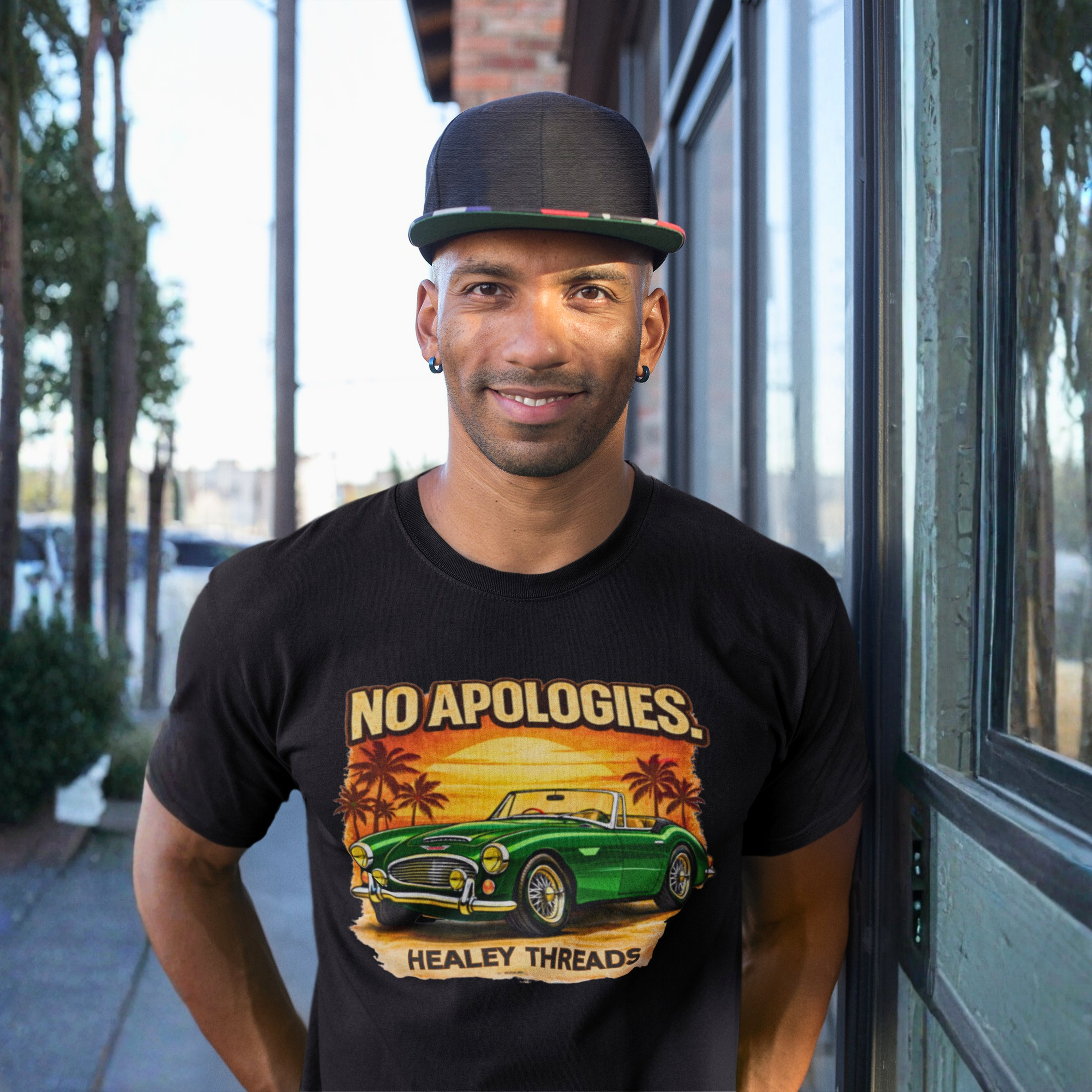 Man wearing a black t-shirt with a graphic Healey car design and text, standing outdoors.