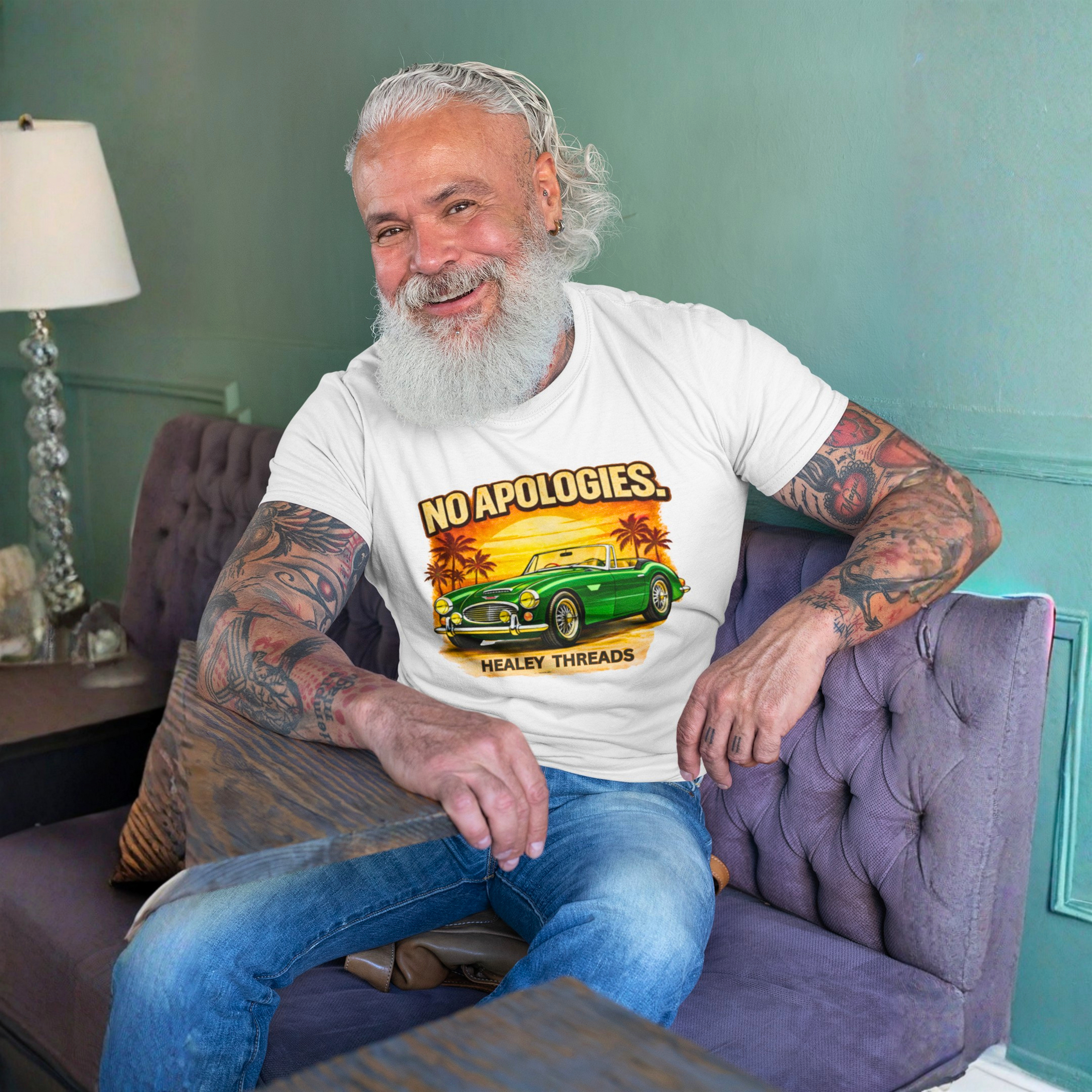 Man sitting on a purple couch wearing a white t-shirt with a graphic Healey car design.