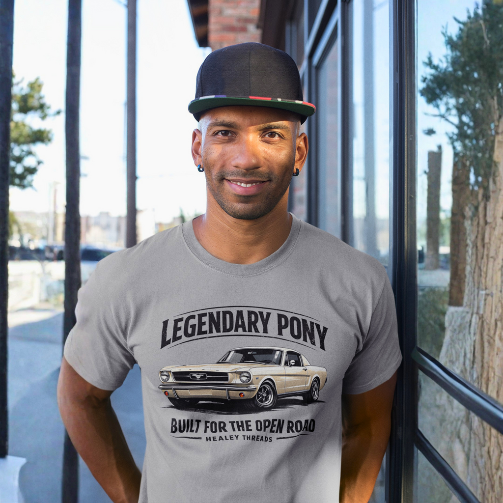 Man wearing a gray t-shirt with a classic car graphic and text, standing in front of a glass door.