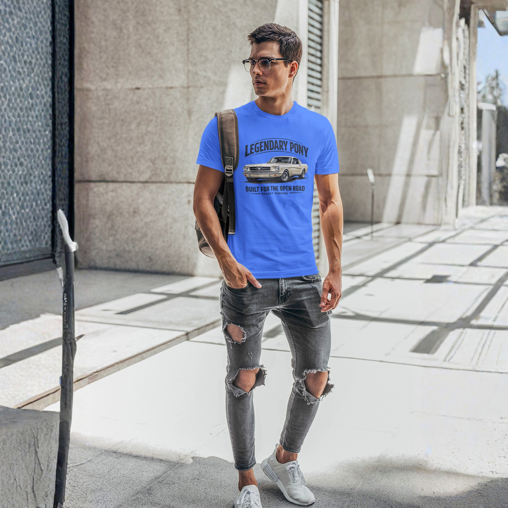 Man wearing a blue t-shirt with a classic car graphic design, standing on a city street.