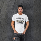 Man wearing a white t-shirt with a classic car graphic and text against a textured gray wall.