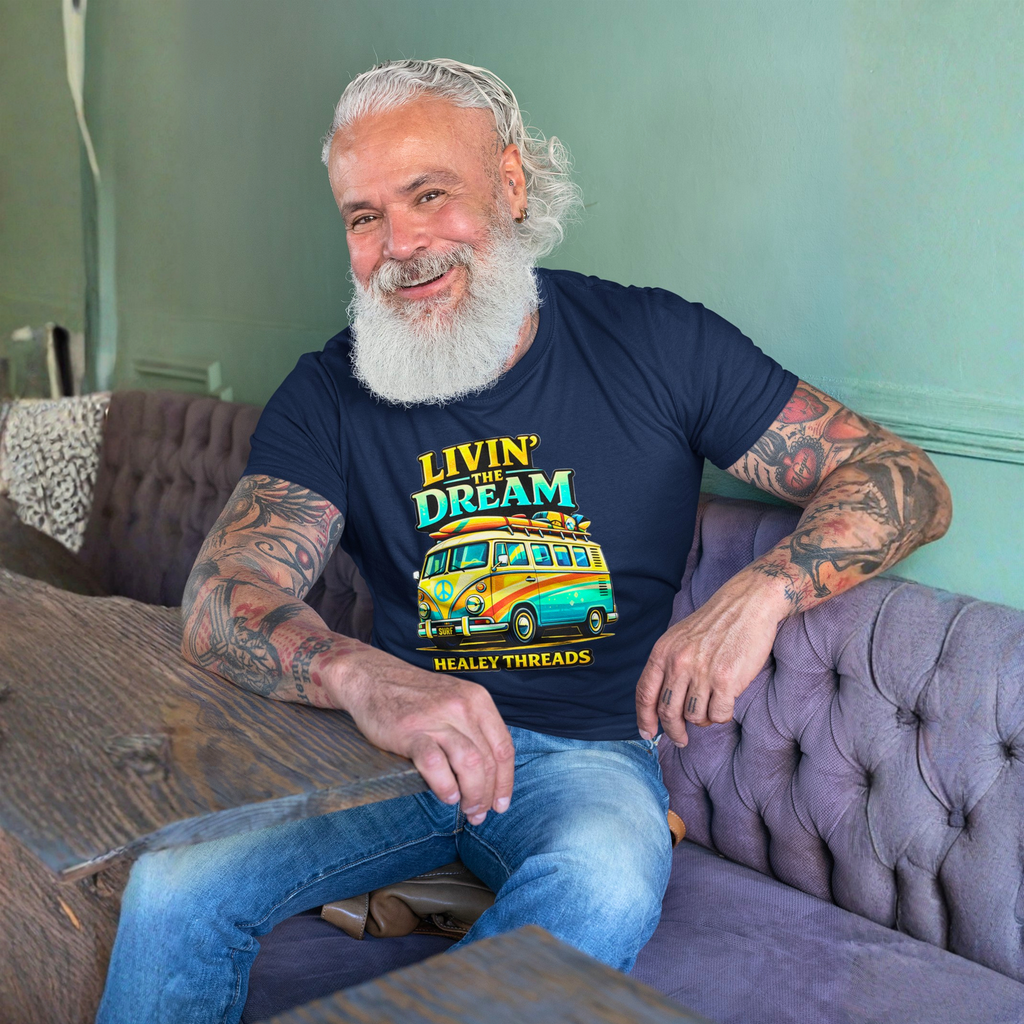 Man with tattoos wearing a navy blue t-shirt with colorful van graphics and text, sitting on a couch.
