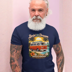 Man wearing a navy blue t-shirt with a graphic design and text, standing against a light pink background.