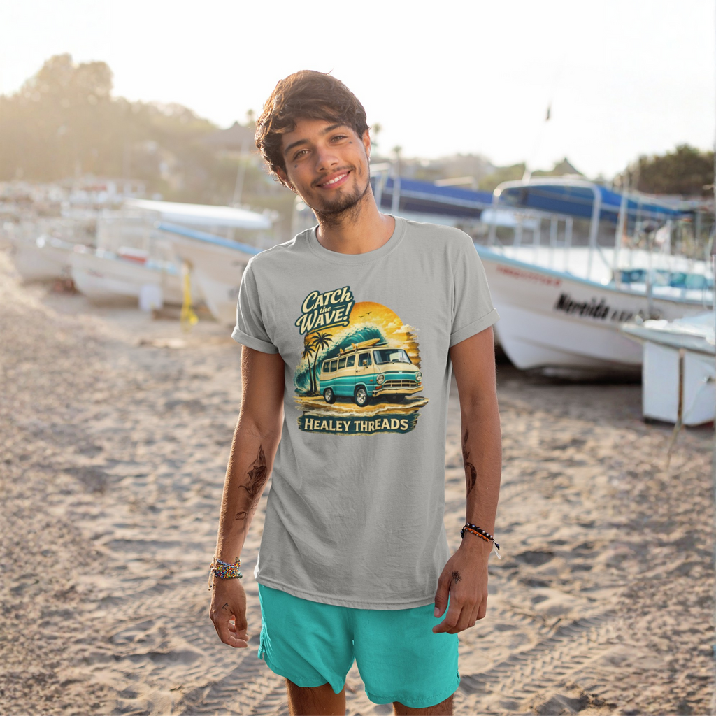 Man wearing a gray t-shirt with a graphic Mopar van design on a beach with boats in the background