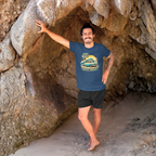 Man standing in a cave wearing a navy blue t-shirt with a graphic Mopar van design.