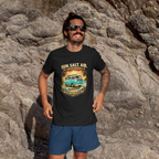 Man wearing a black t-shirt with a graphic van design standing on rocky terrain.