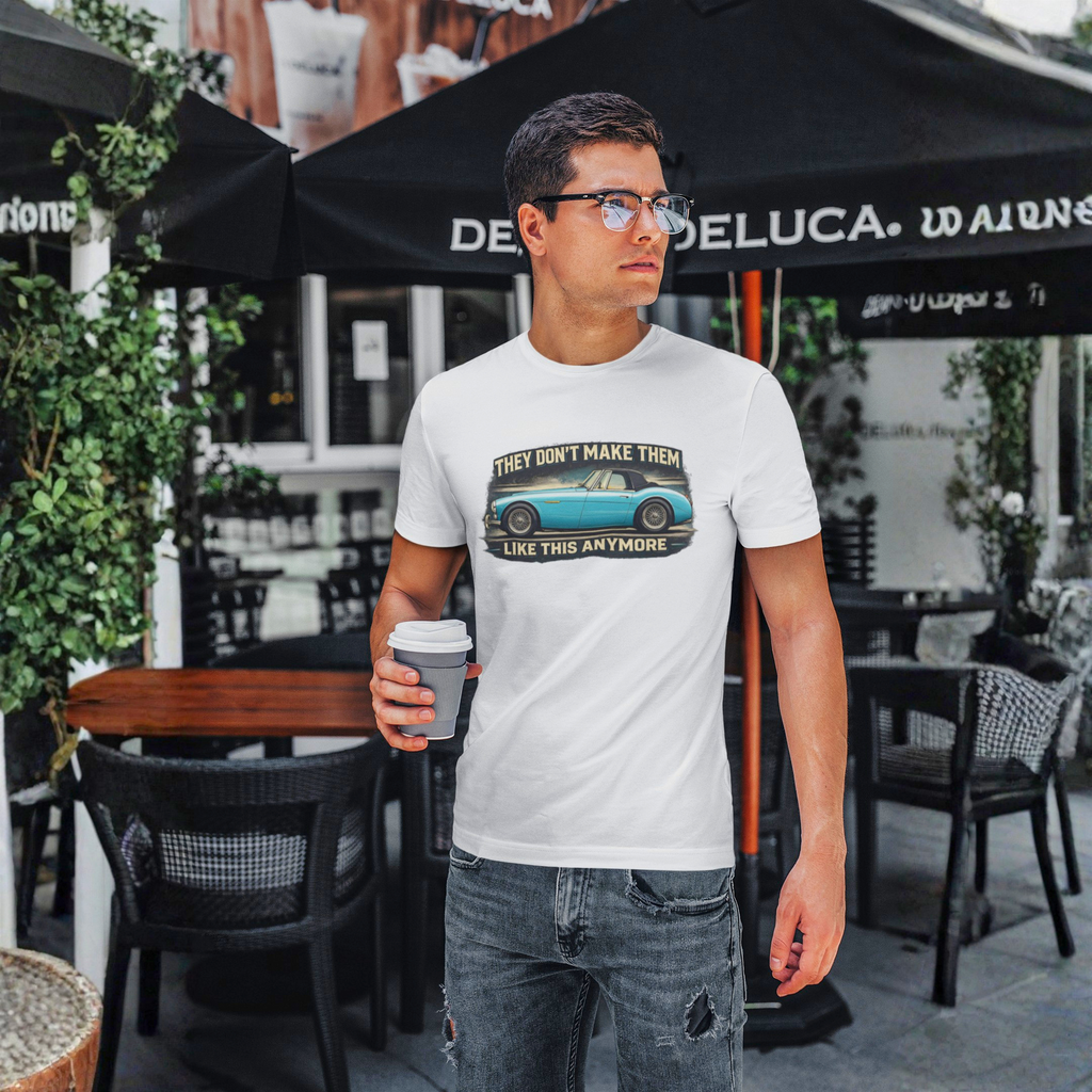 Man wearing a white t-shirt with a graphic design, standing outdoors under an umbrella.