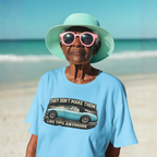 Woman wearing a light blue t-shirt with a graphic Healey and text on a beach.