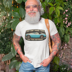 Man wearing a white t-shirt with a graphic Healey design and text, standing outdoors among greenery.