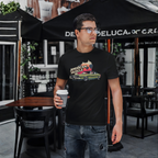 Man holding a coffee cup wearing a black t-shirt with a graphic design in an outdoor cafe setting.