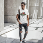 Man wearing a white t-shirt with graphics and ripped jeans in an urban setting
