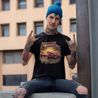 Man wearing a black 'American Muscle' t-shirt with a red car graphic, sitting on a ledge with a building in the background.