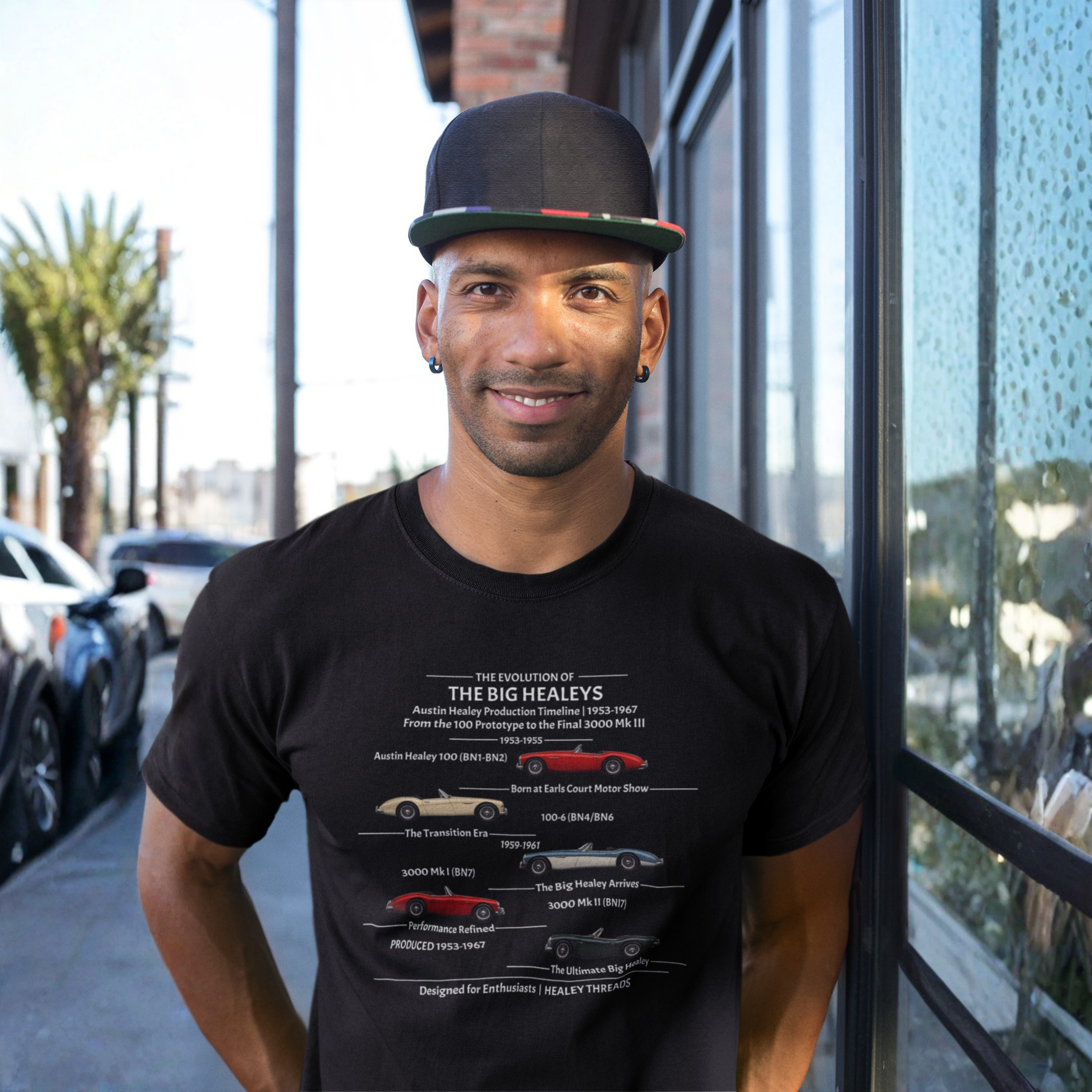 Man wearing a black t-shirt with a Healey timeline graphic design standing on a street