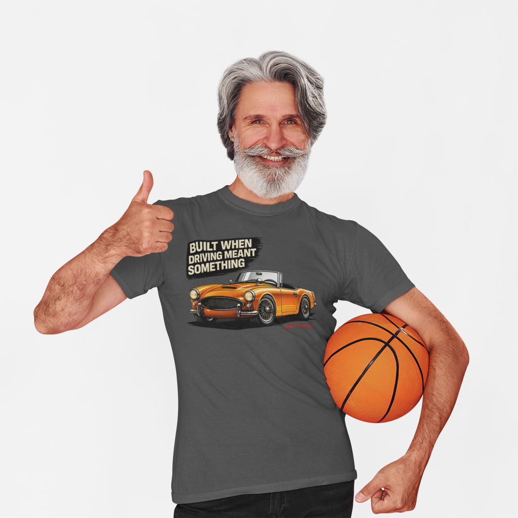 Man wearing a gray t-shirt with a car graphic and text, holding a basketball on a white background