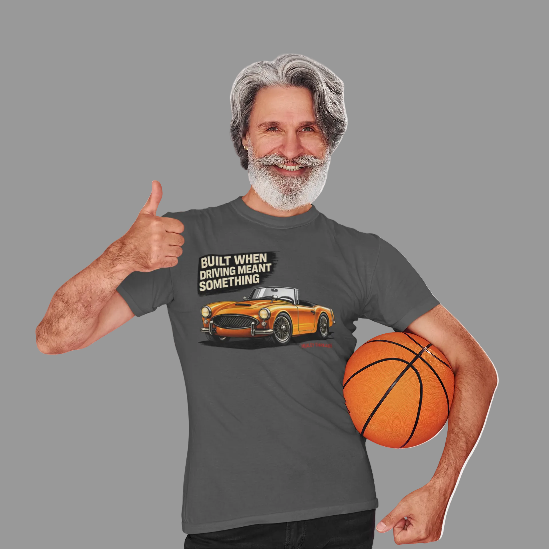 Man wearing a gray t-shirt with a British car graphic and text, holding a basketball on a white background