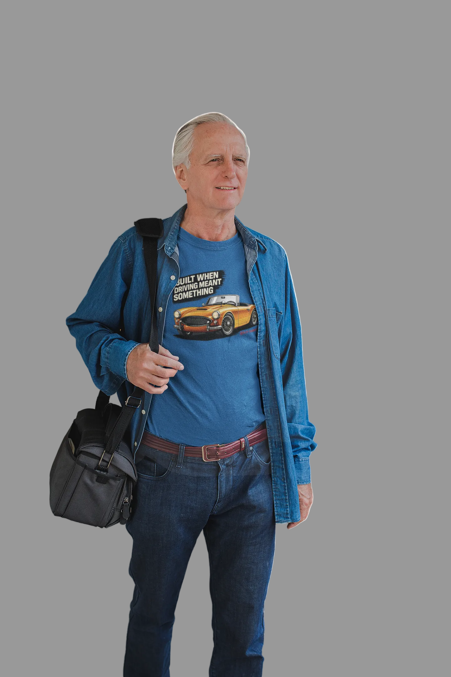 Man wearing a royal blue shirt with a British classic car graphic design, holding a black bag on a white background