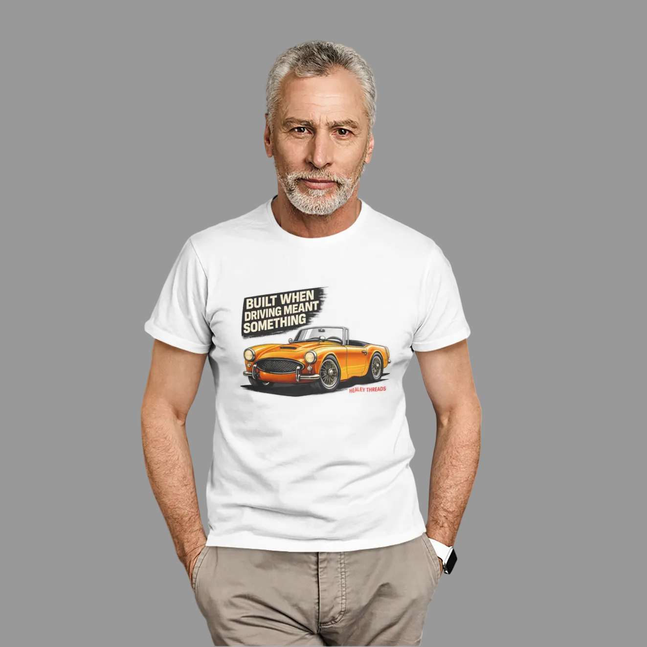 Man wearing a white t-shirt with a British classic car graphic design on a plain background.