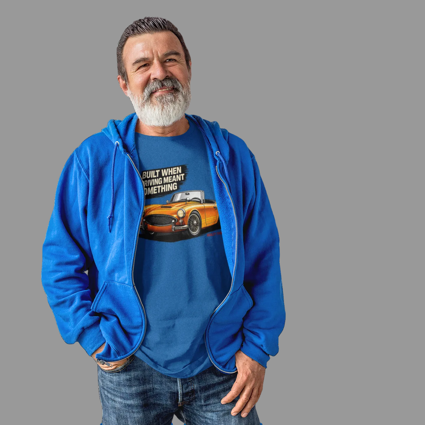 Man wearing a royal blue t-shirt and British classic car graphic design on a gray background.