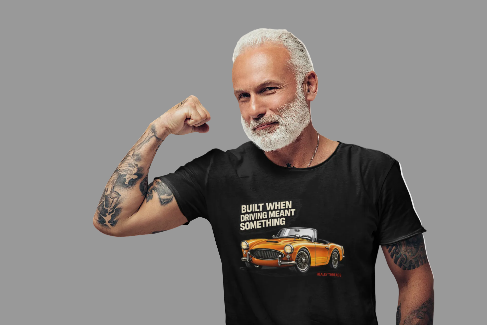 Man wearing a black t-shirt with a British car graphic and text, flexing his arm on a white background 