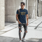 Man wearing a navy blue t-shirt with a Austin Healey logo and ripped jeans walking on a city street.