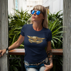 Woman wearing a navy blue t-shirt with a gold Healey emblem, standing outdoors with greenery in the background.