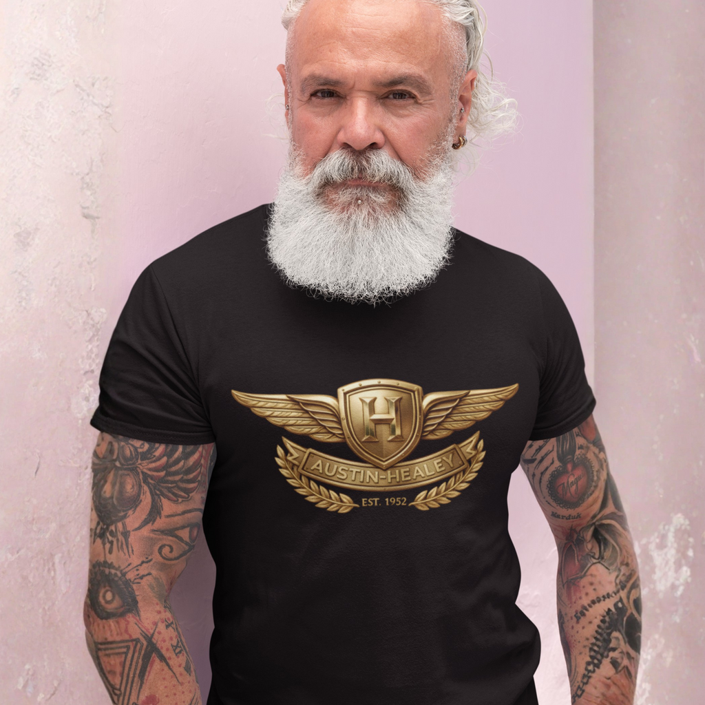 Man wearing a black t-shirt with a gold Healey logo against a light pink background