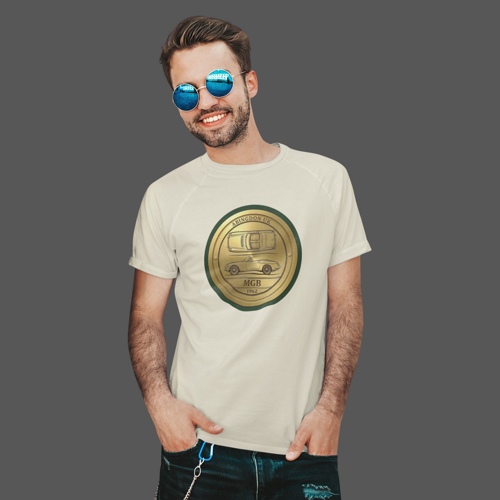 Man wearing a natural t-shirt with a gold classic car emblem and text, standing against a gray background