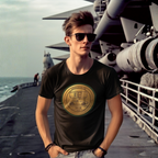 Man wearing a black t-shirt with a gold classic car emblem on a naval ship deck.