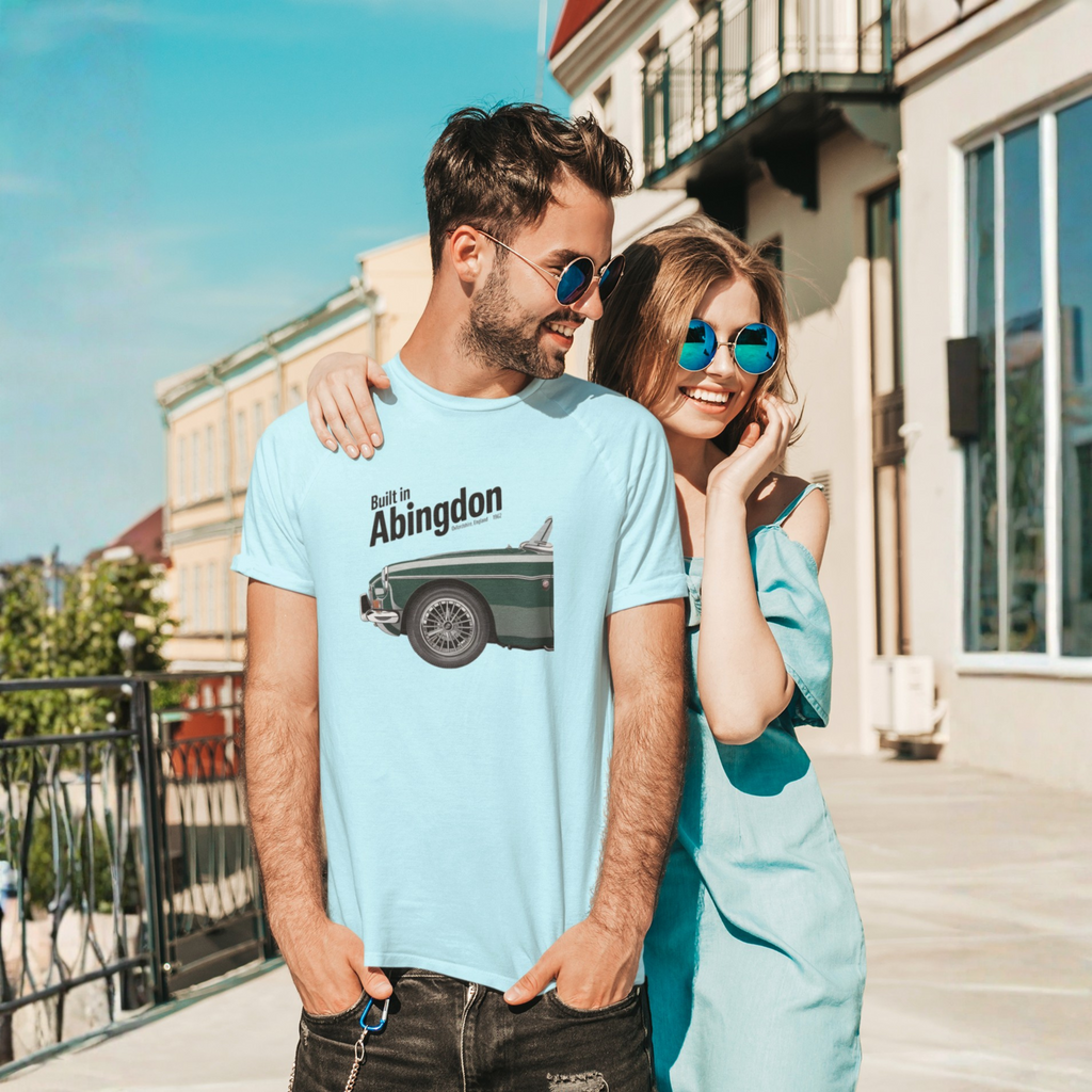 Man and woman standing together on a sunny day, both wearing sunglasses and light blue shirts with a classic car design.