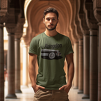 Man wearing a military green t-shirt with a graphic classic car design and text, standing in an architectural setting.