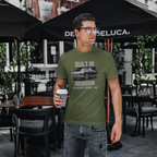 Man wearing a military green t-shirt with text and a classic car graphic, holding a coffee cup outdoors.