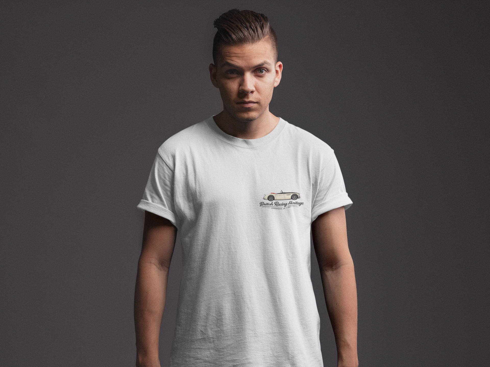 Man wearing a white t-shirt with a Healey car graphic and black text on a dark background