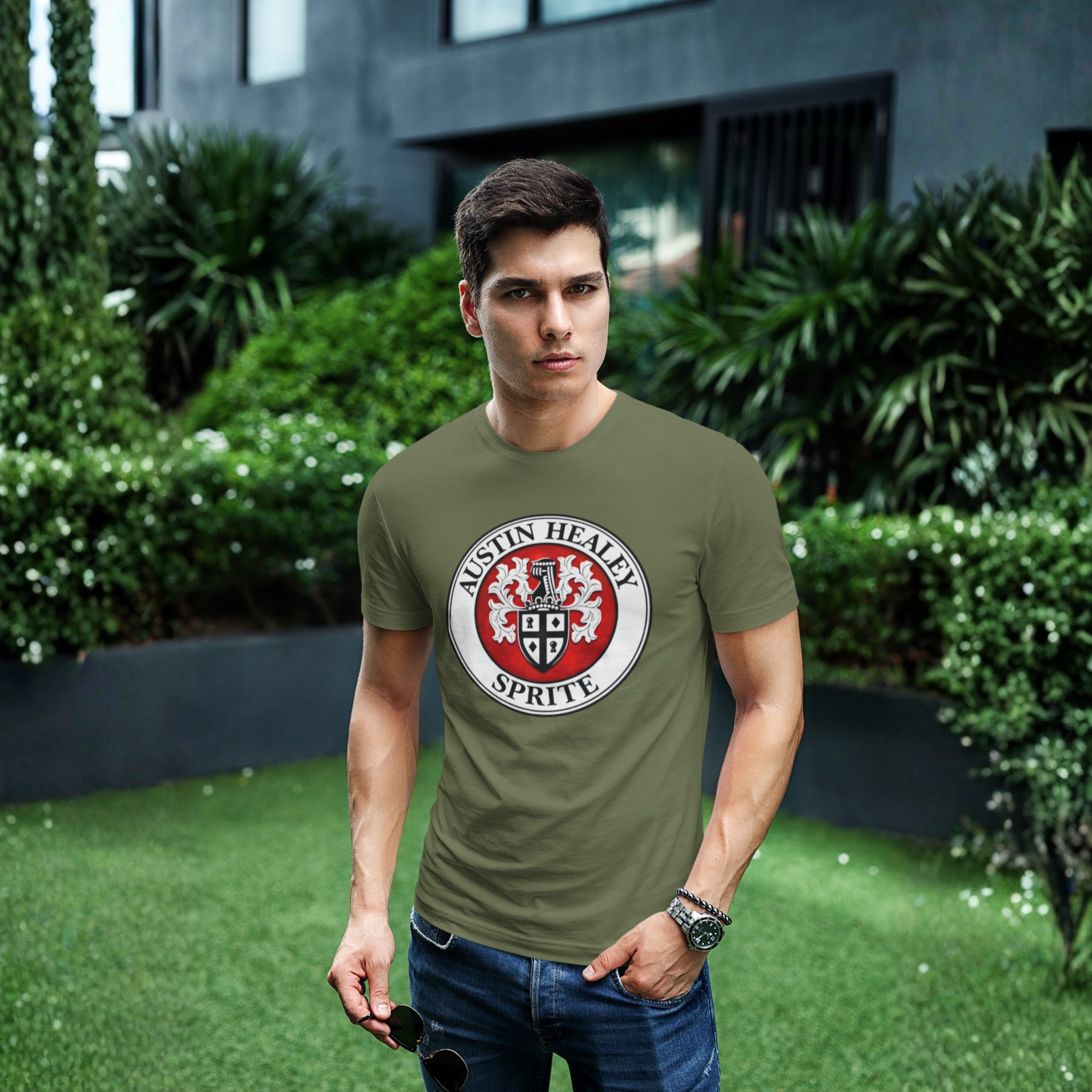 Man wearing a military green t-shirt with a Austin Healey Sprite logo standing outdoors.